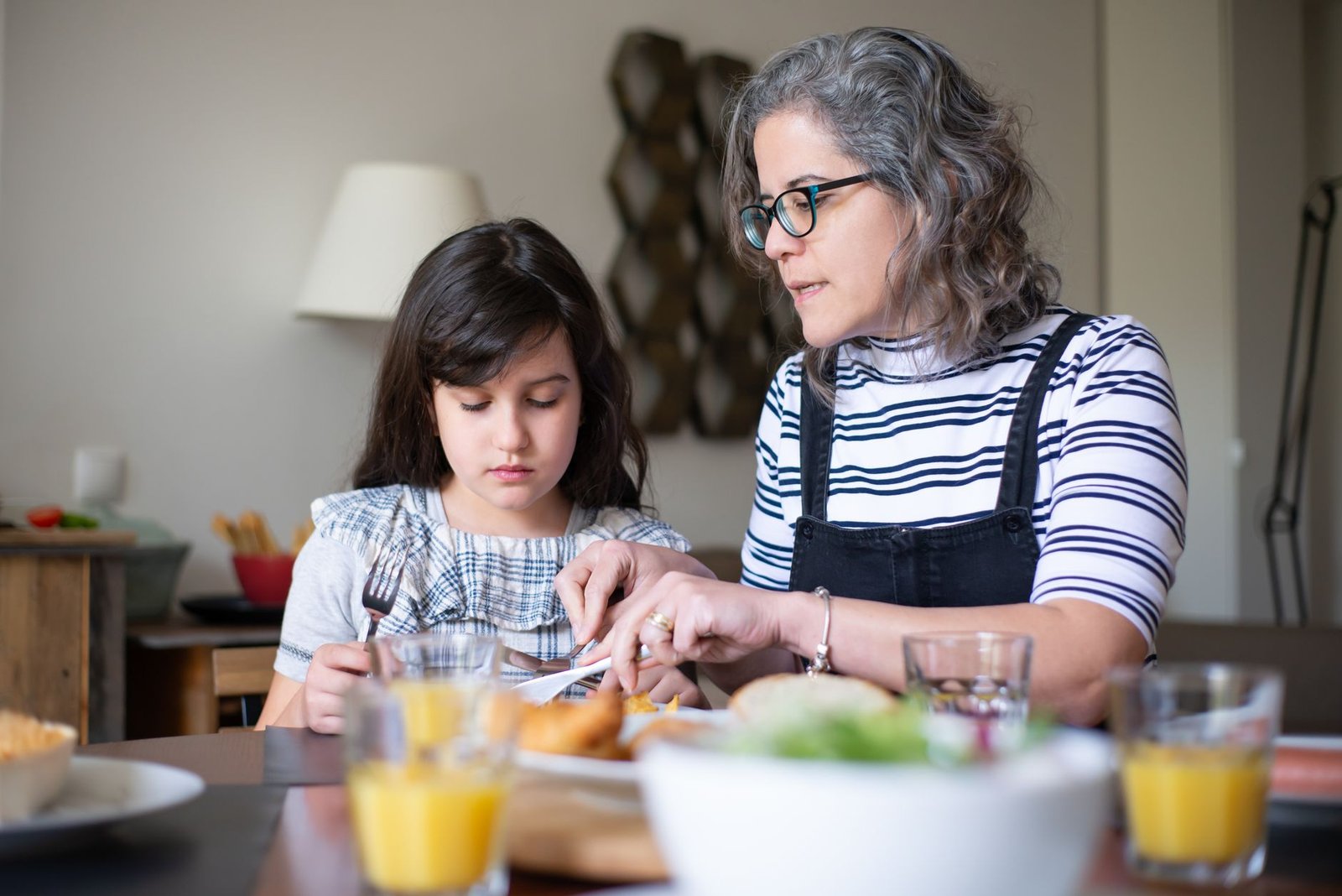 Parent talking gently with a child at the kitchen table about a family member's cancer diagnosis